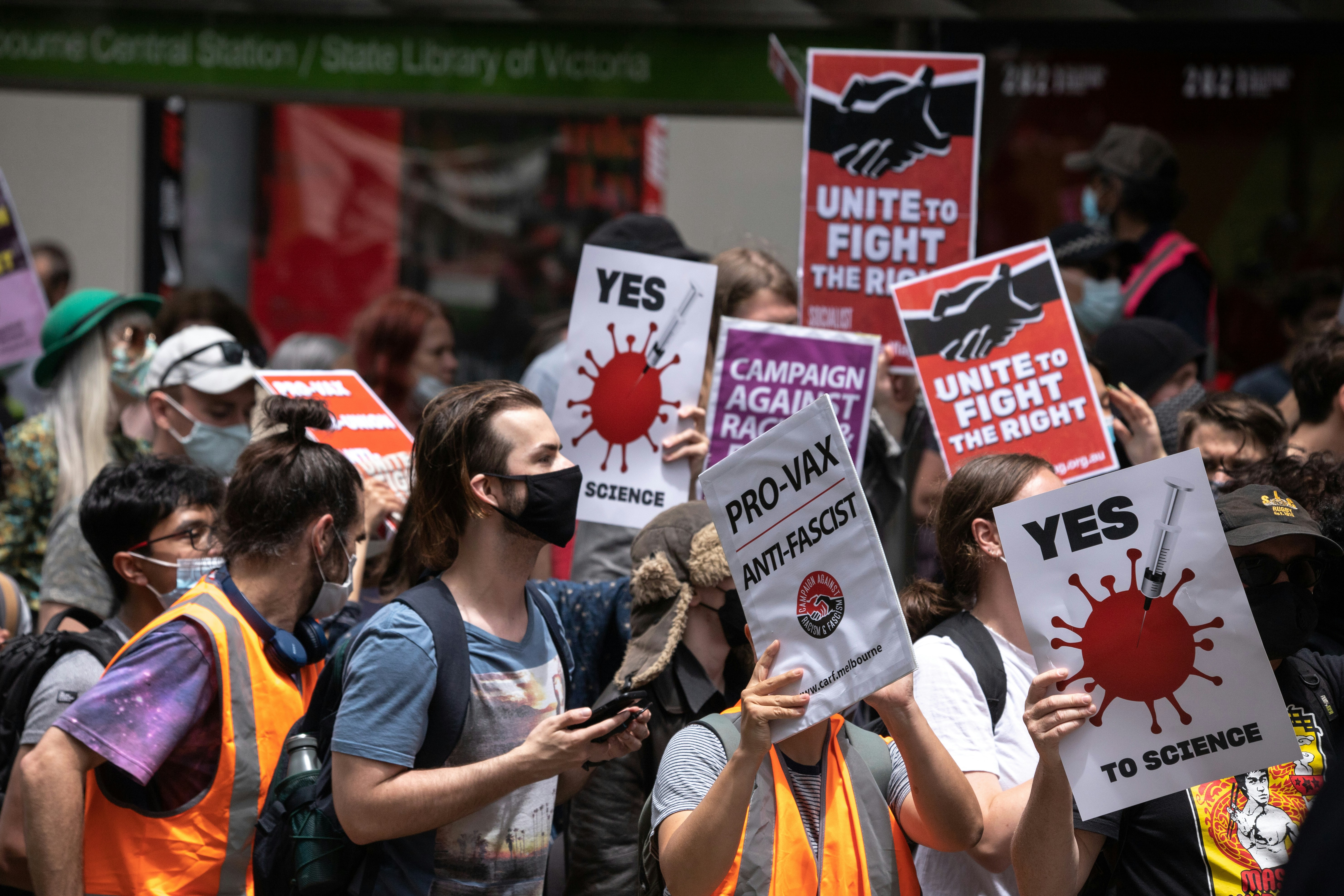 A group of people holding signs and wearing masks photo – Free ...
