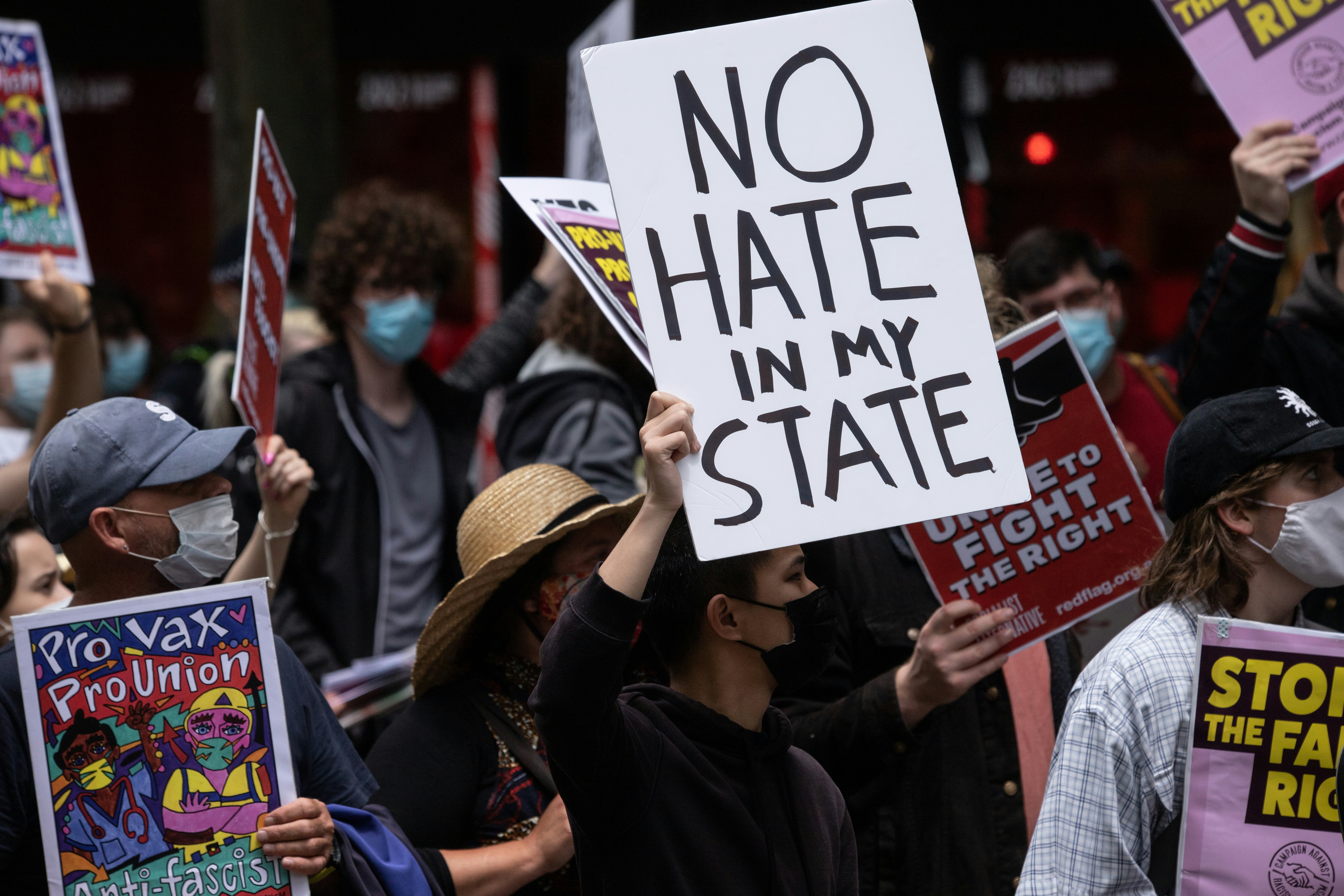a group of people holding signs and wearing masks