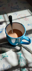 A vibrant baby blue mug filled with steaming coffee on a sunny windowsill.