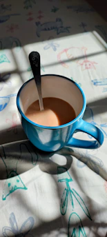 A vibrant baby blue mug filled with steaming coffee on a sunny windowsill.