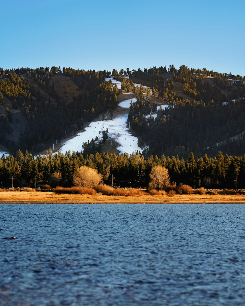 a mountain covered in snow next to a lake