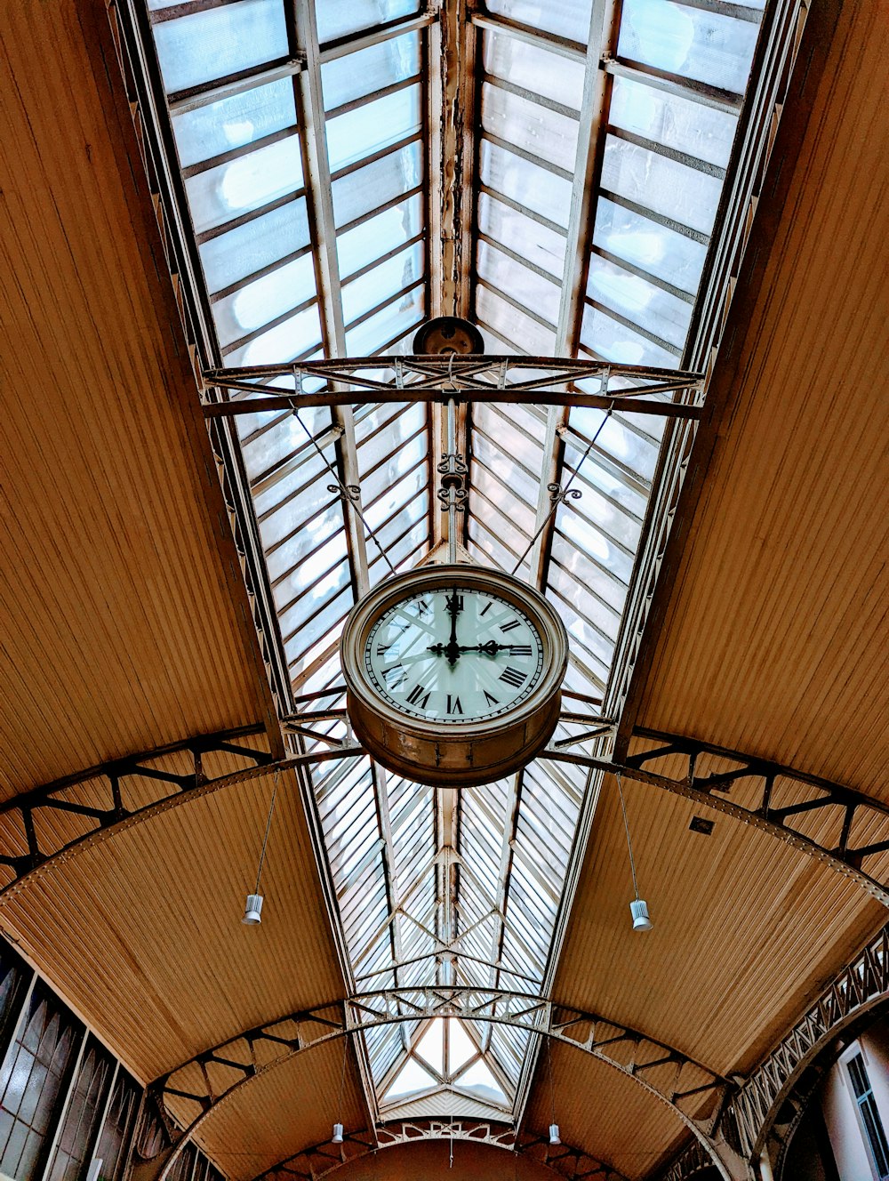 a clock hanging from the ceiling of a train station