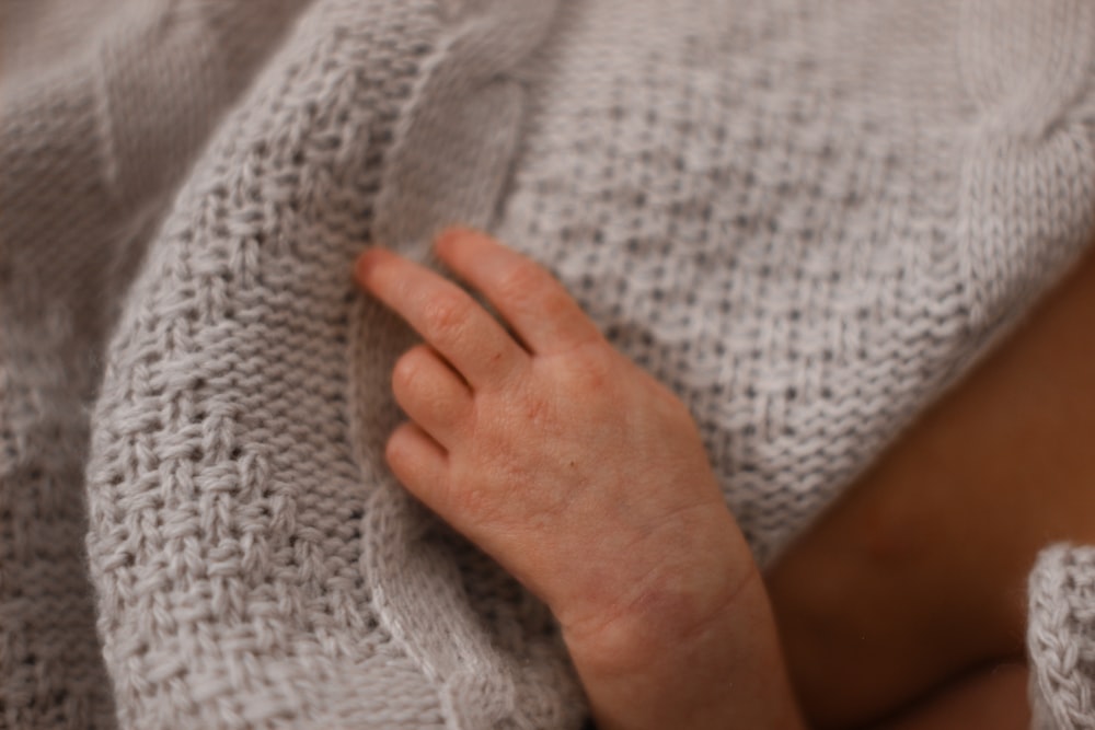 a person wrapped in a blanket with their hand on top of the blanket