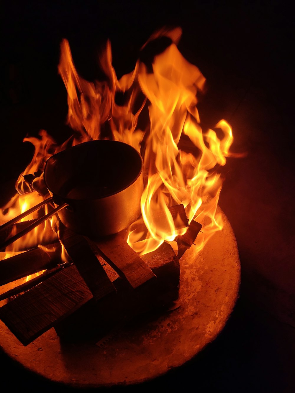 a fire burning in the dark with a bowl on top of it
