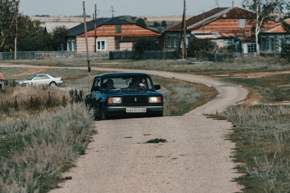 a black car driving down a dirt road