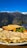 A plate of food including a golden omelette, two slices of toasted bread, and a mix of sautéed vegetables such as bell peppers, broccoli, and carrots. The meal is set against a backdrop of a mountainous landscape with snow-capped peaks and a clear blue sky.