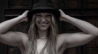 A smiling customer holding a custom crochet hat with intricate patterns.