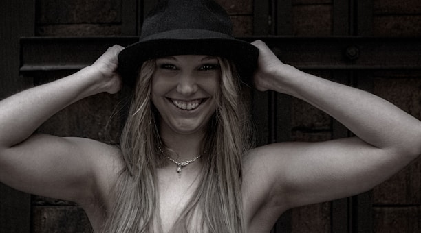A smiling customer holding a custom crochet hat with intricate patterns.