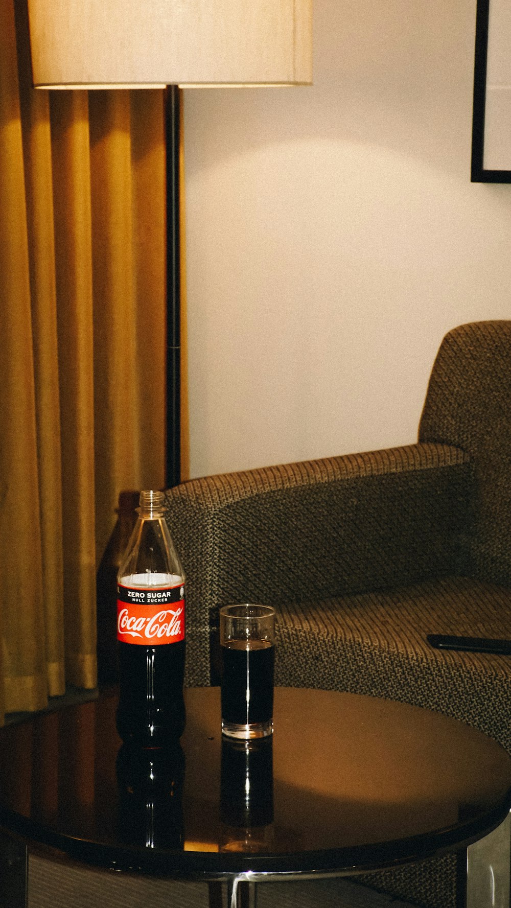a coca cola bottle sitting on top of a table next to a glass
