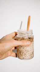 a person holding a jar of food with a wooden spoon in it