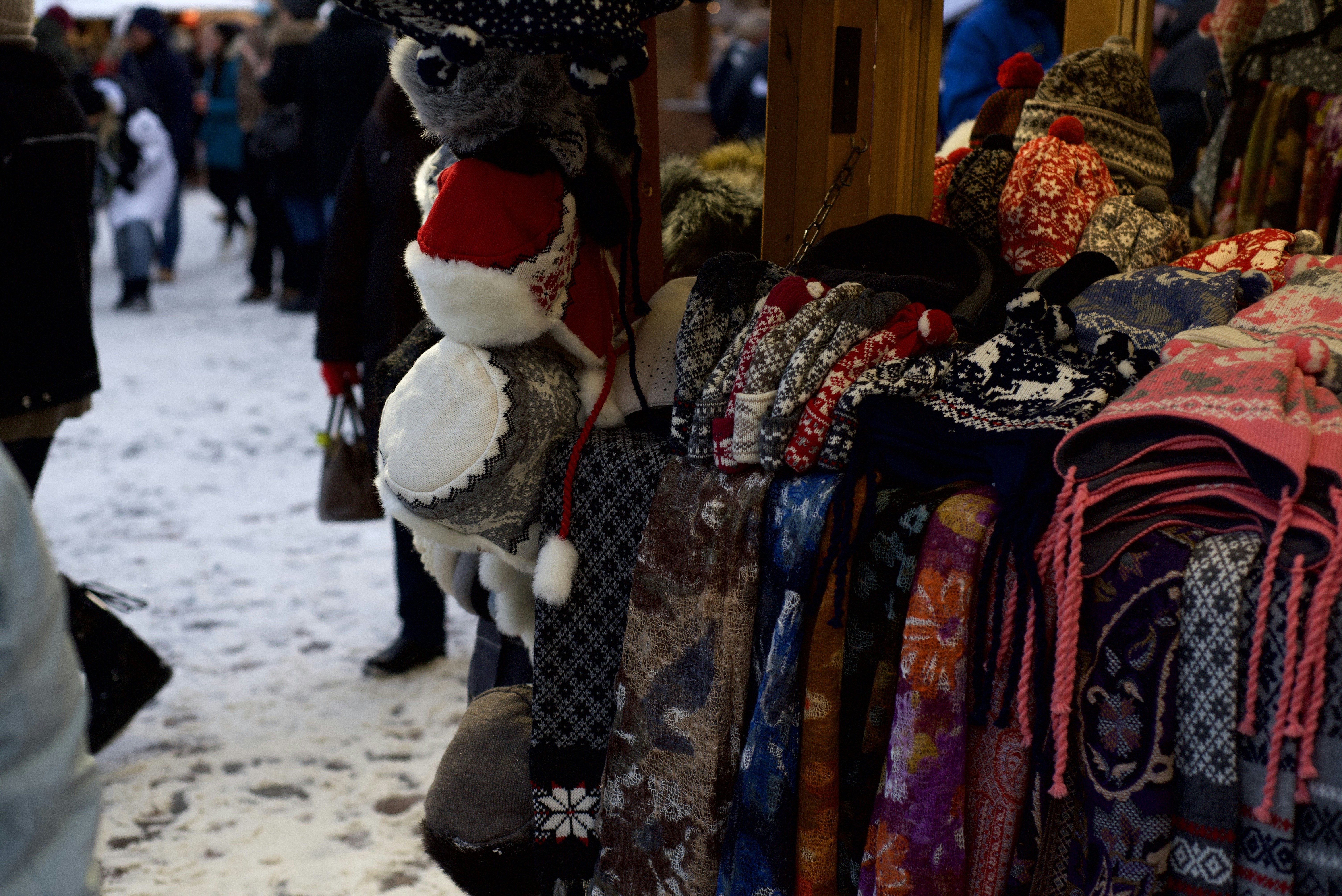 a bunch of scarves and hats hanging on a rack