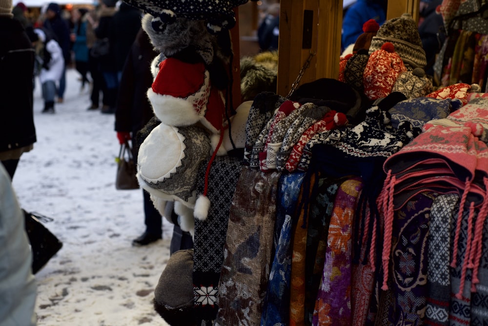 a bunch of scarves and hats hanging on a rack