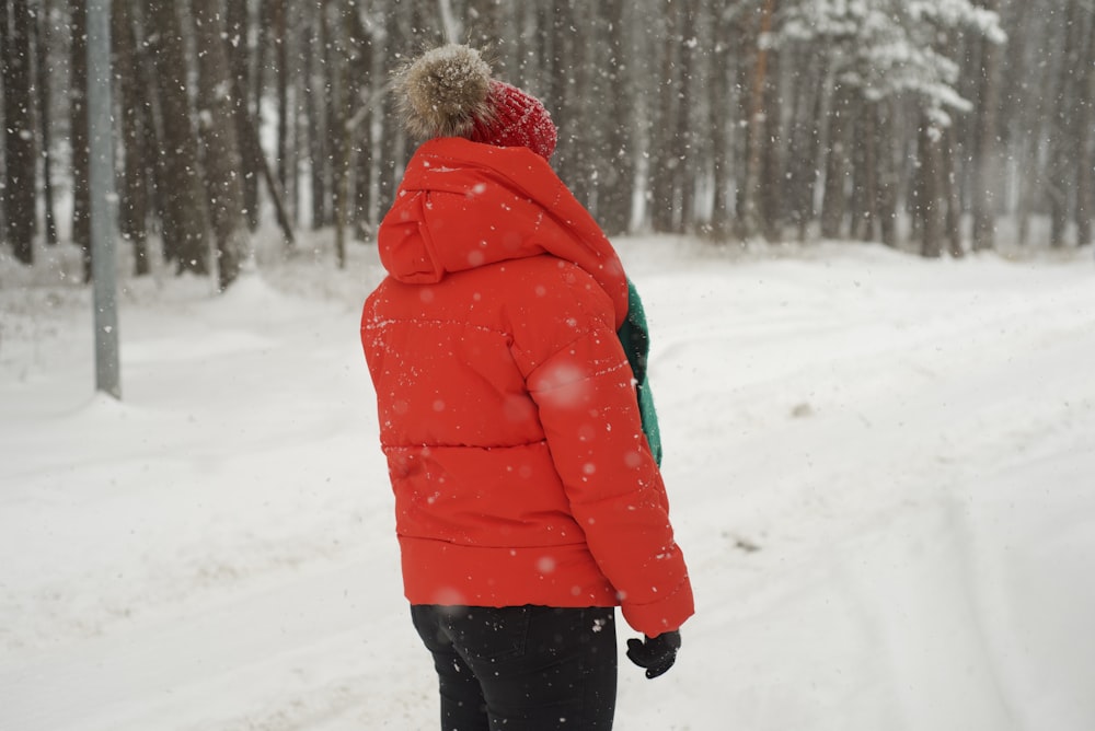 a person in a red jacket standing in the snow