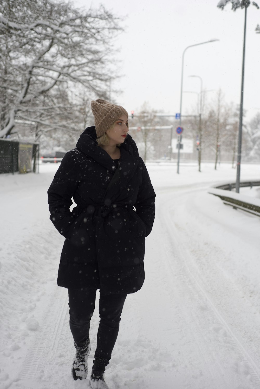 Eine Frau geht eine schneebedeckte Straße entlang