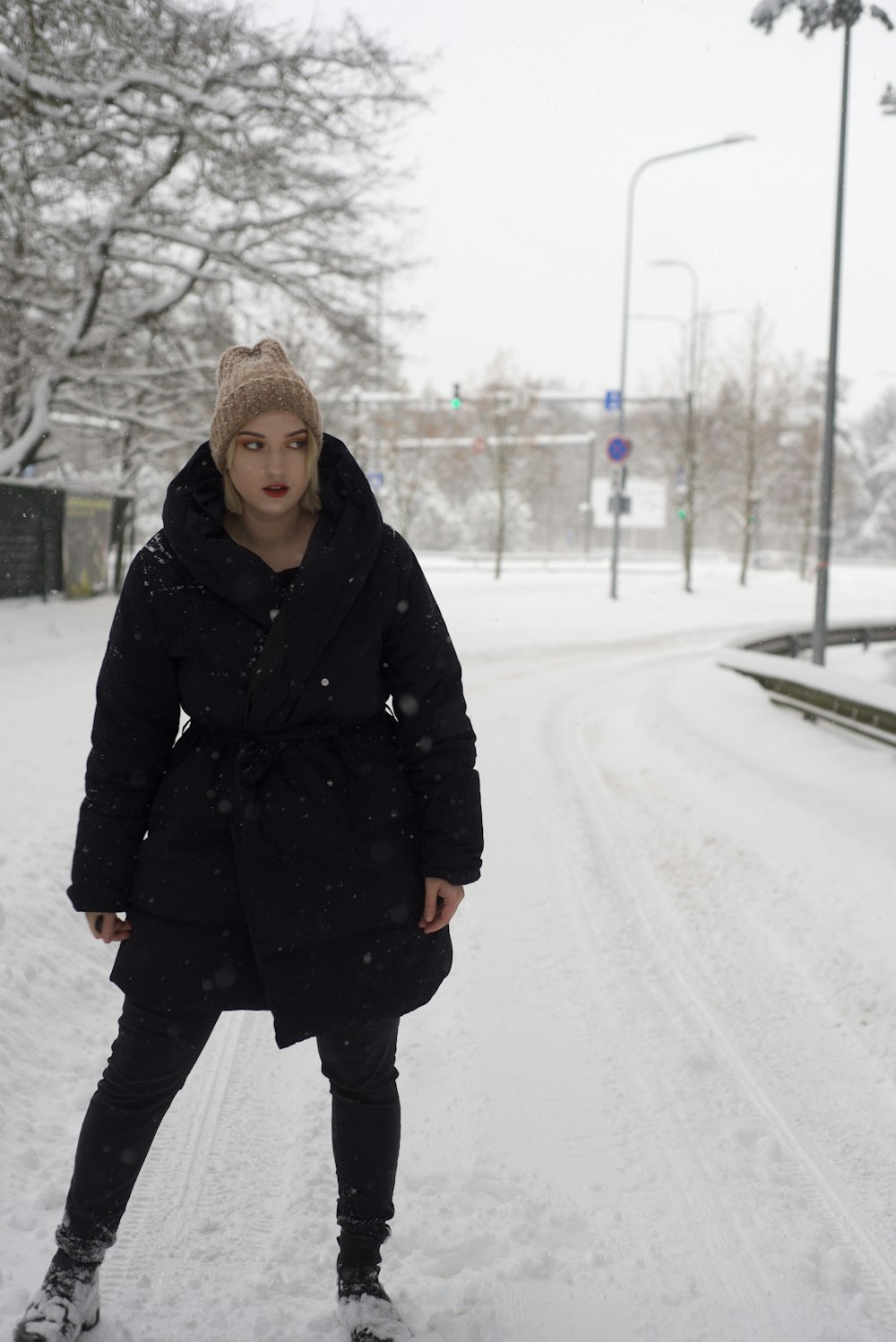 a woman standing in the snow in a black coat