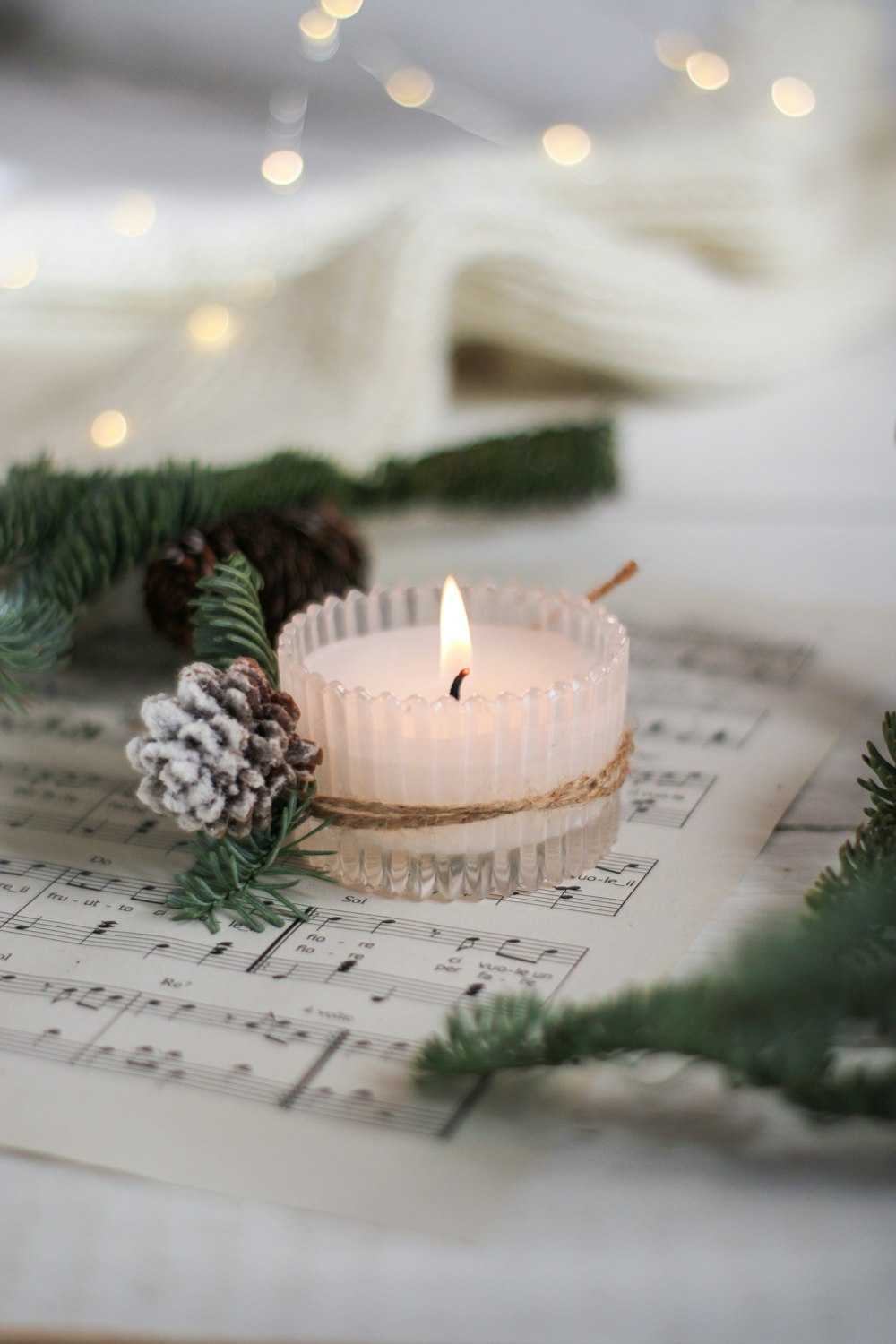 a lit candle sitting on top of a sheet of music
