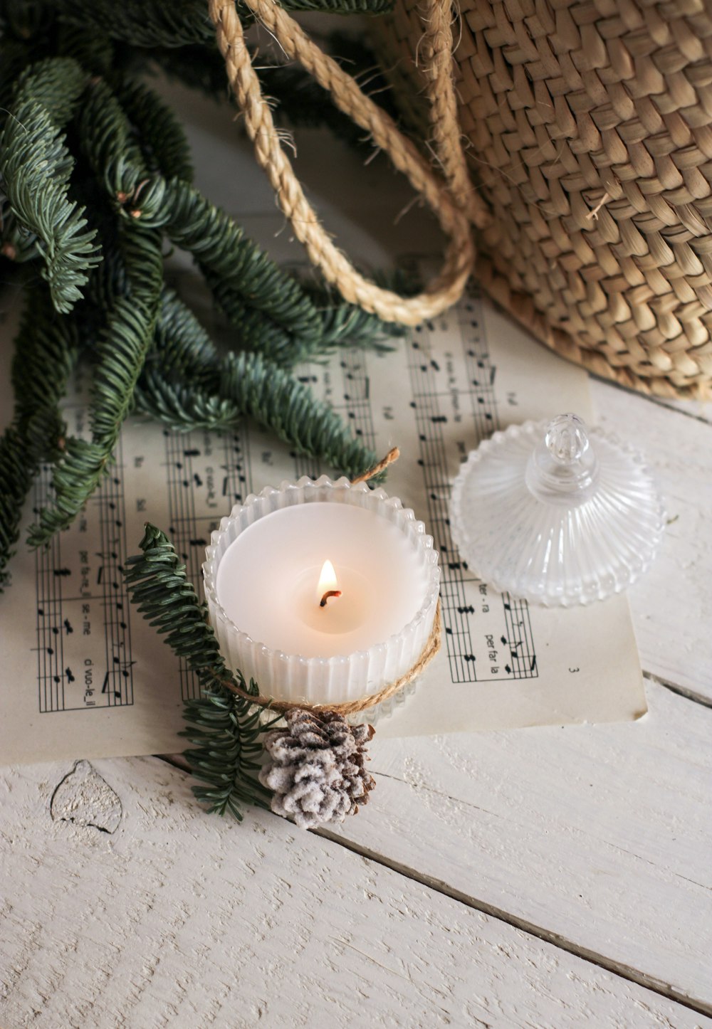 a white candle sitting on top of a table next to a pine cone