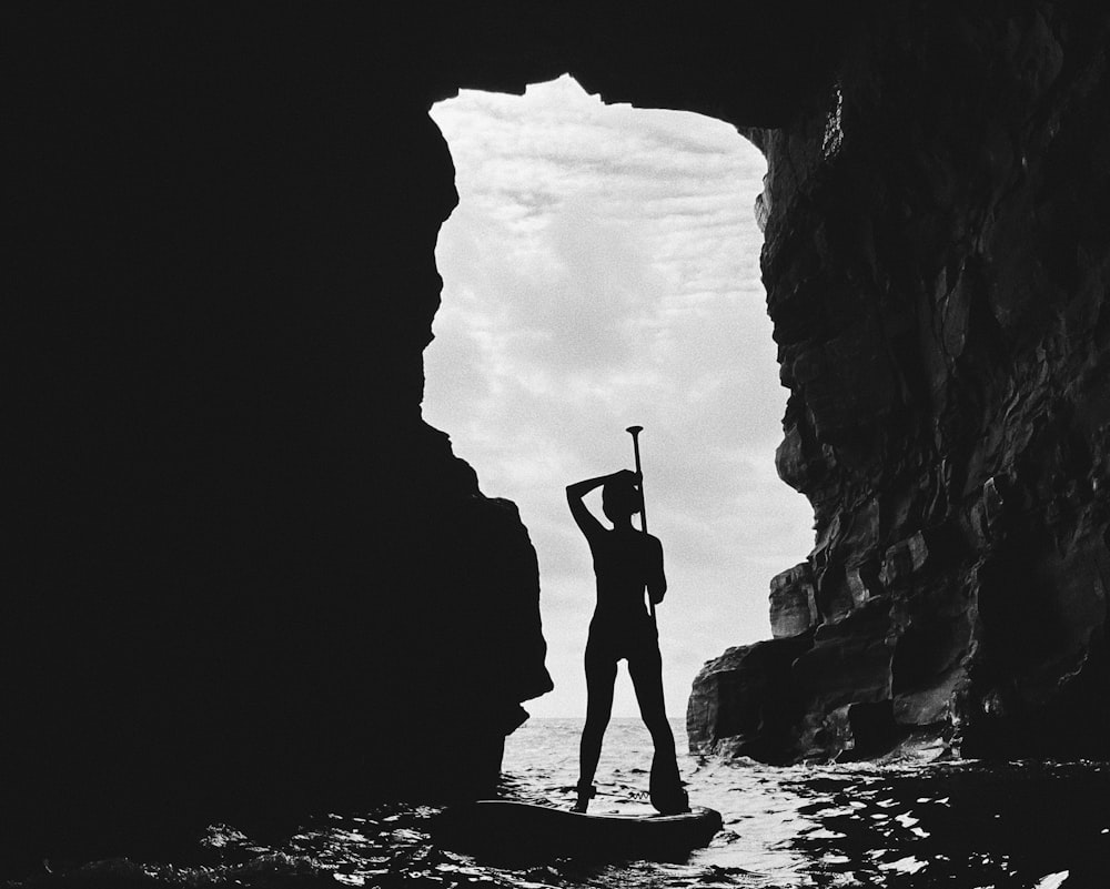 a person standing in a cave with a surfboard