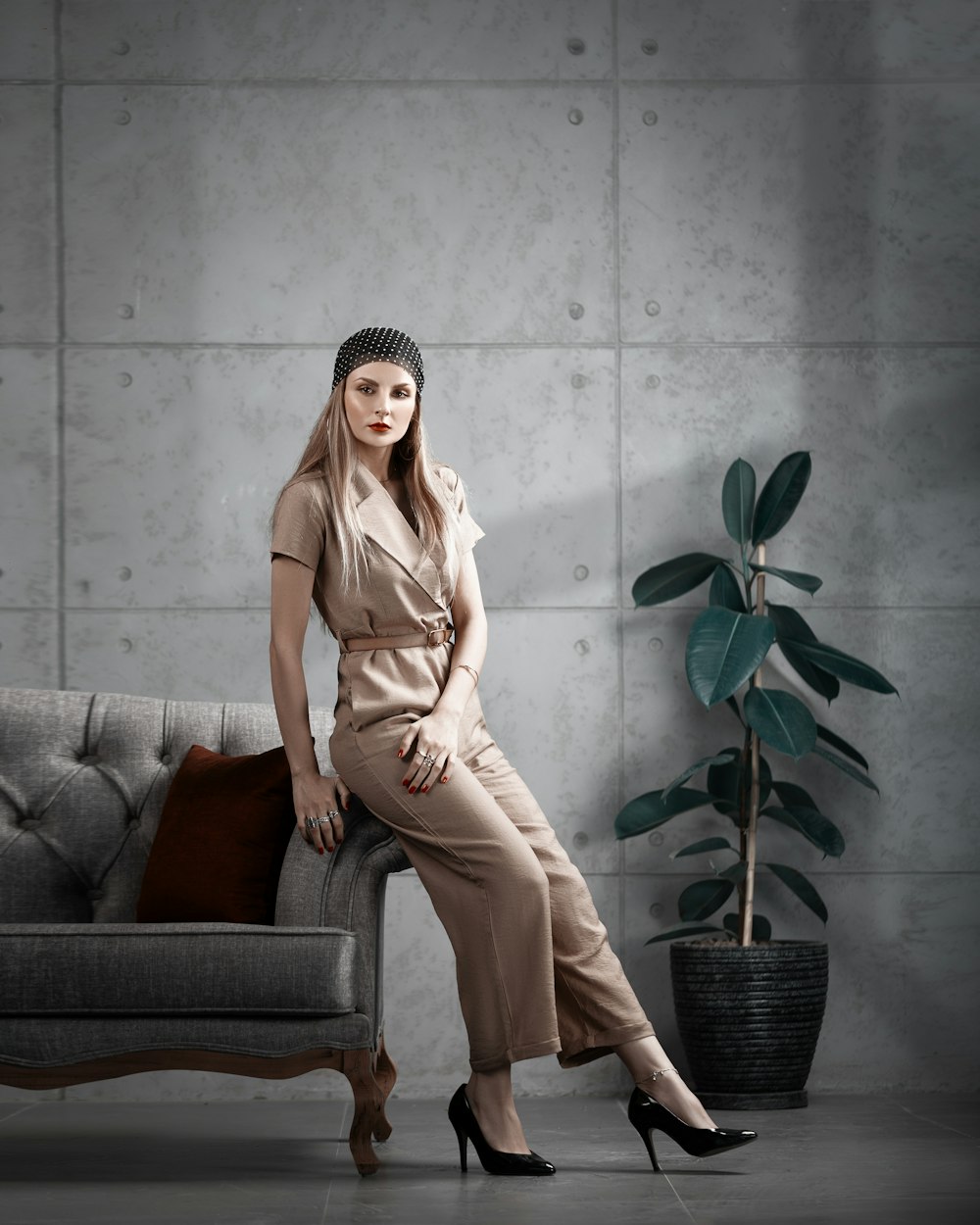 a woman sitting on a couch next to a potted plant