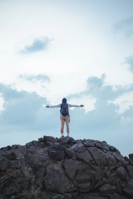 A happy traveler with a backpack, standing on a mountain peak, representing travel insurance.