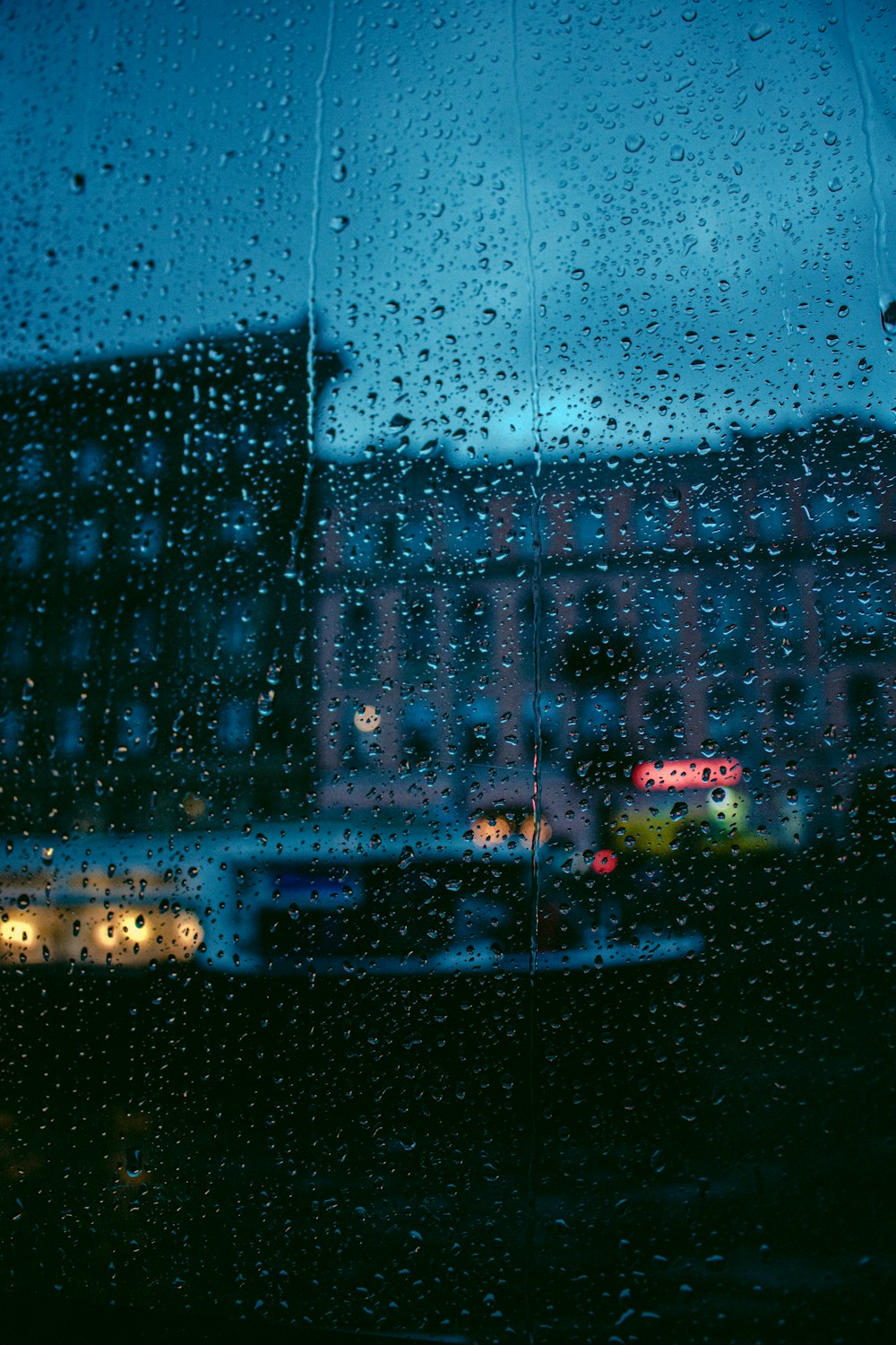 una vista di un edificio attraverso una finestra coperta dalla pioggia
