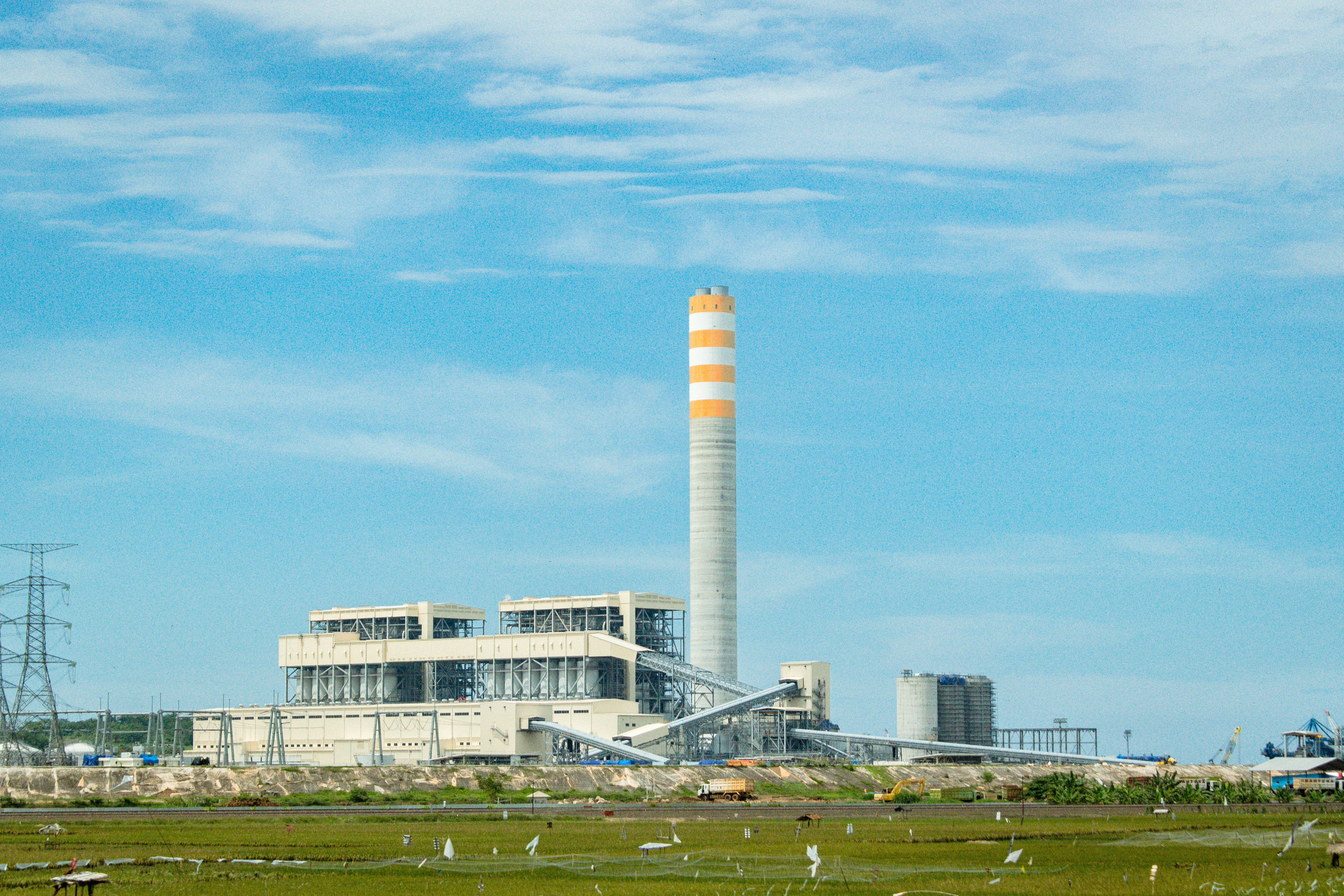 a factory with a large tower in the middle of a field