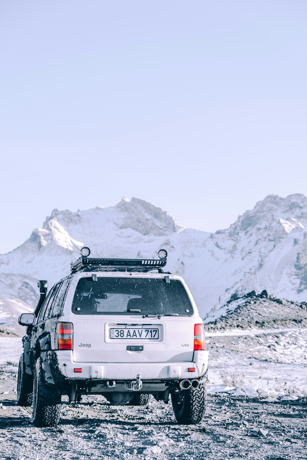 a white suv parked on top of a snow covered field