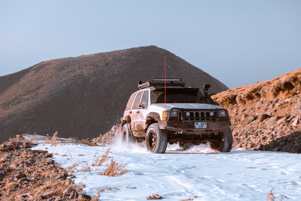 a white truck driving down a snow covered road