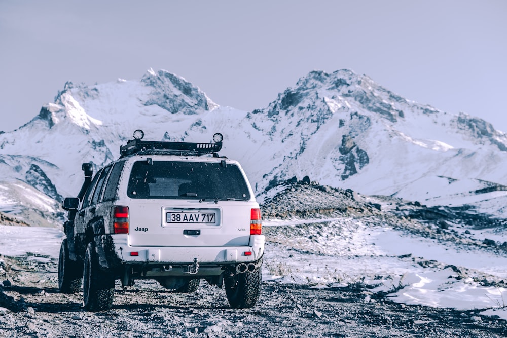 a white suv parked on top of a snow covered mountain