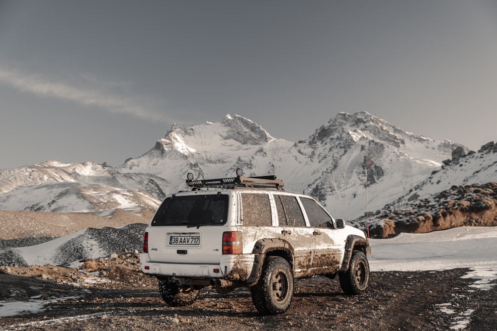 a white suv parked in front of a mountain range