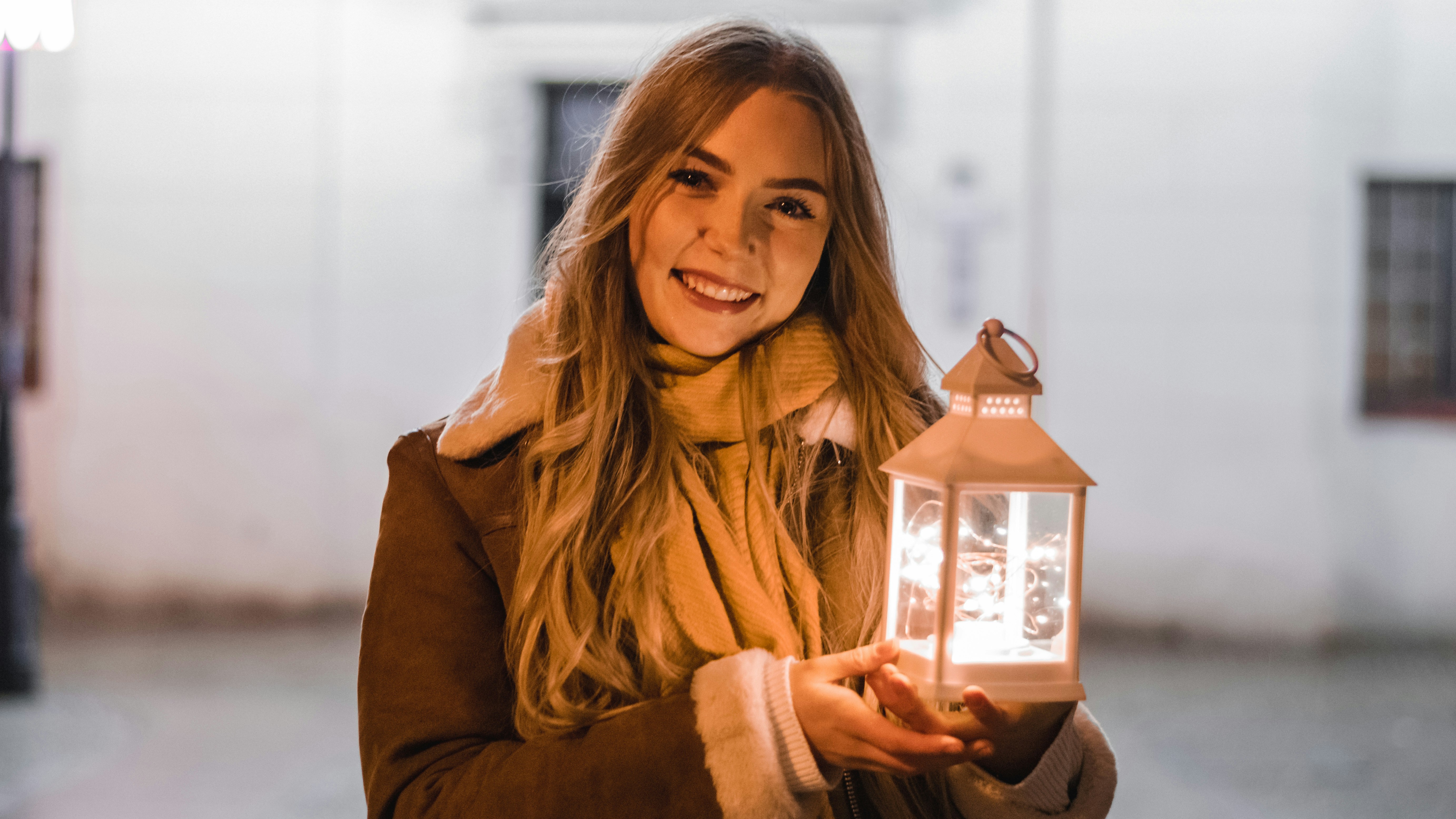 Una mujer sosteniendo una linterna en sus manos