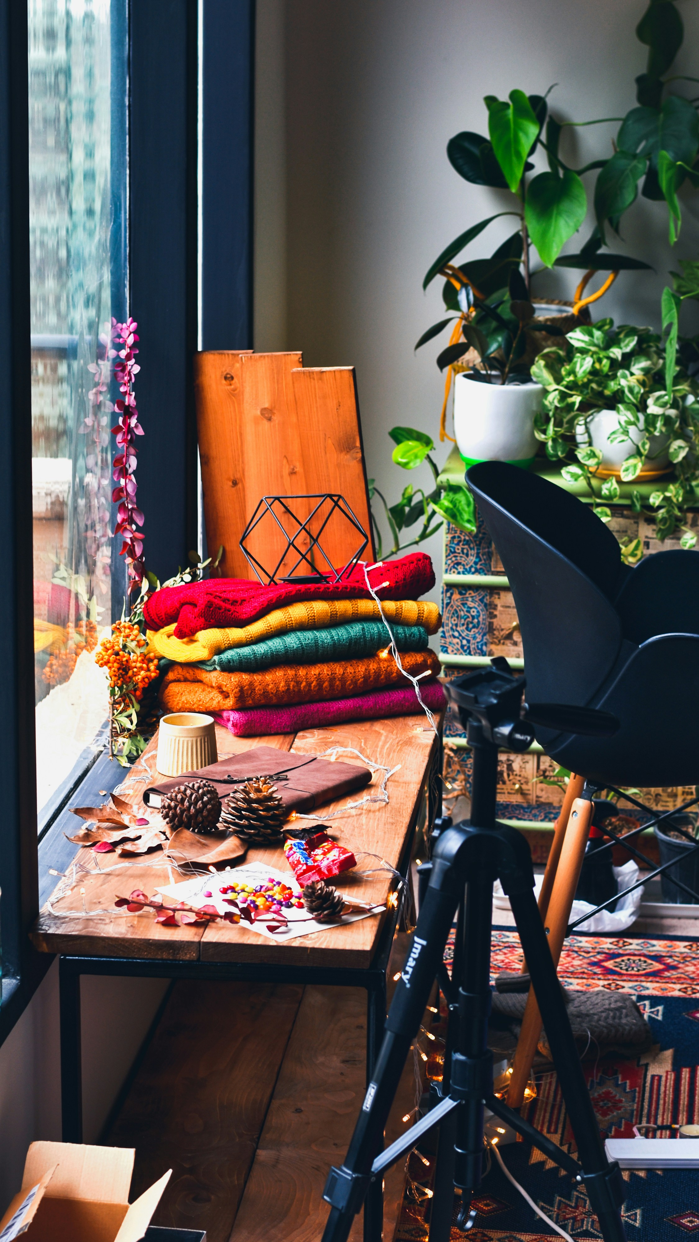 Knitted garments and decorations sit on a wooden window shelf.