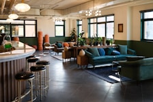 Sunlit lounge area with plush sofas and vibrant purple accents.