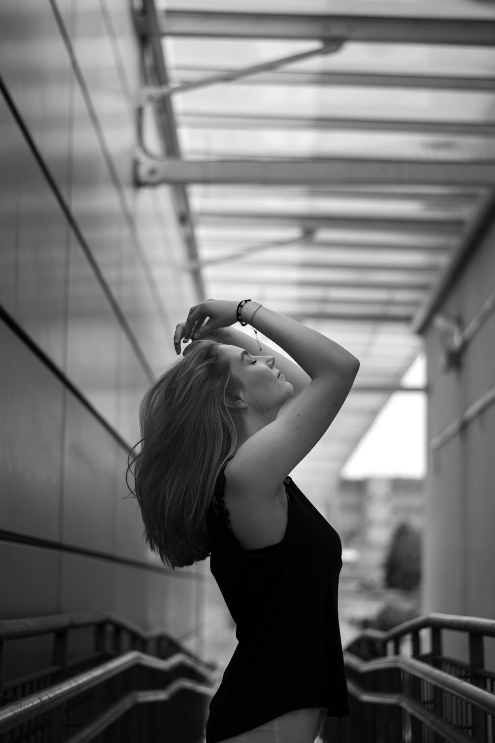 a woman in a black shirt is standing on an escalator