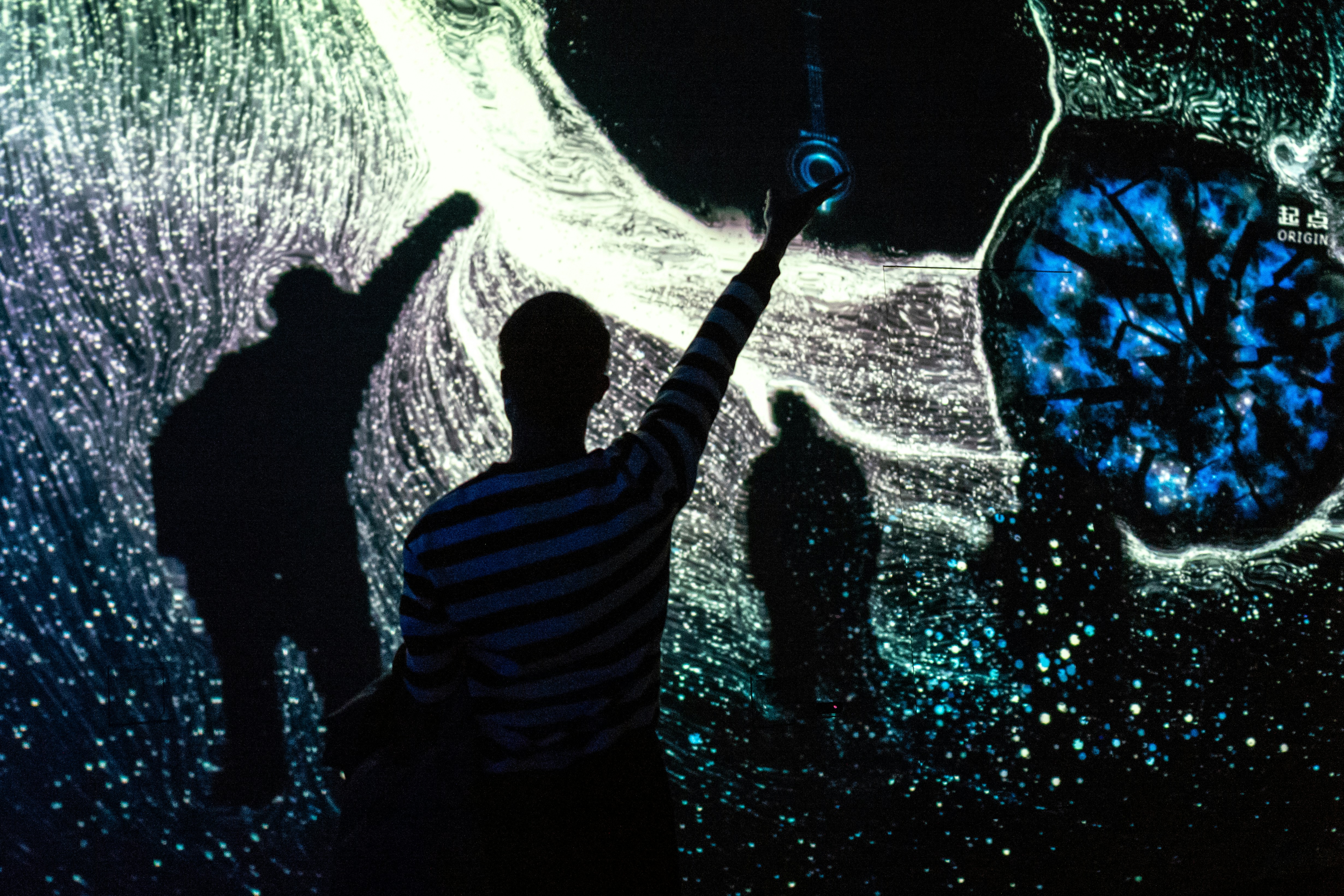 Person reaches towards swirling blue and white digital light patterns.