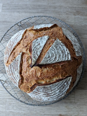 Artisan bread loaves cooling on a wire rack with flour dusted on surrounding surfaces.