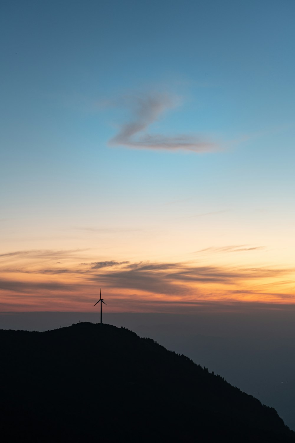 a windmill on top of a hill at sunset