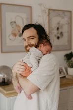 A smiling new dad holding his baby gently while learning parenting tips.