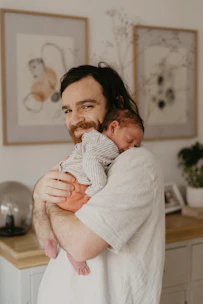 A smiling new dad holding his baby gently while learning parenting tips.