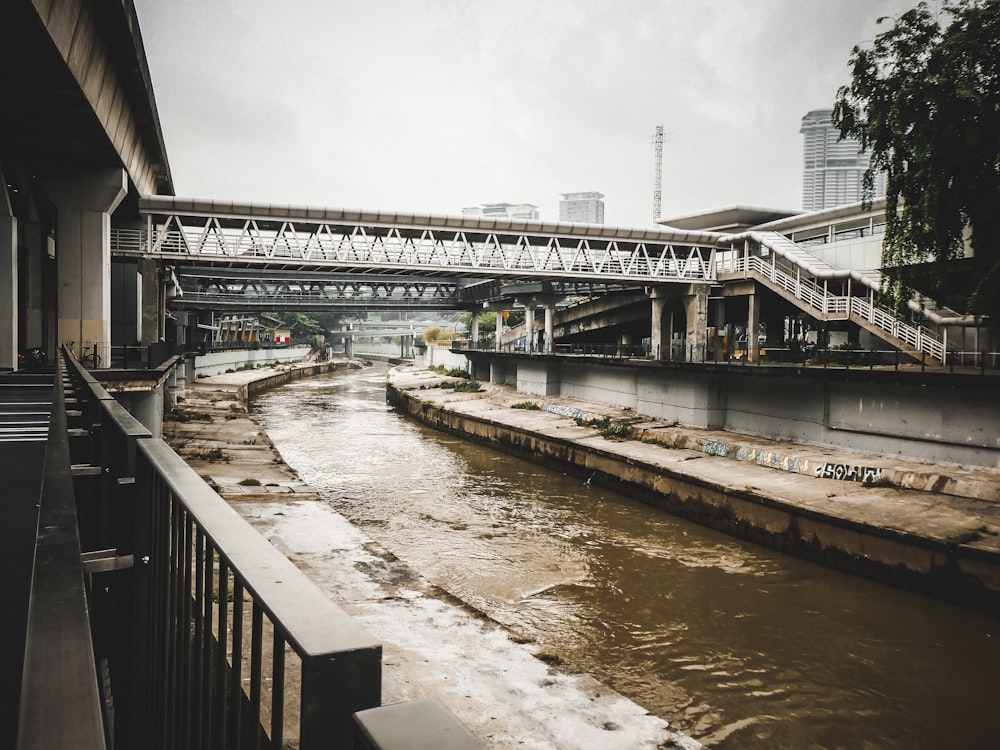 a river running under a bridge next to a tall building