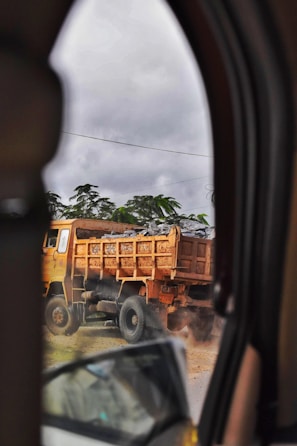 A large dump truck loaded with rocks driving on a rugged dirt road