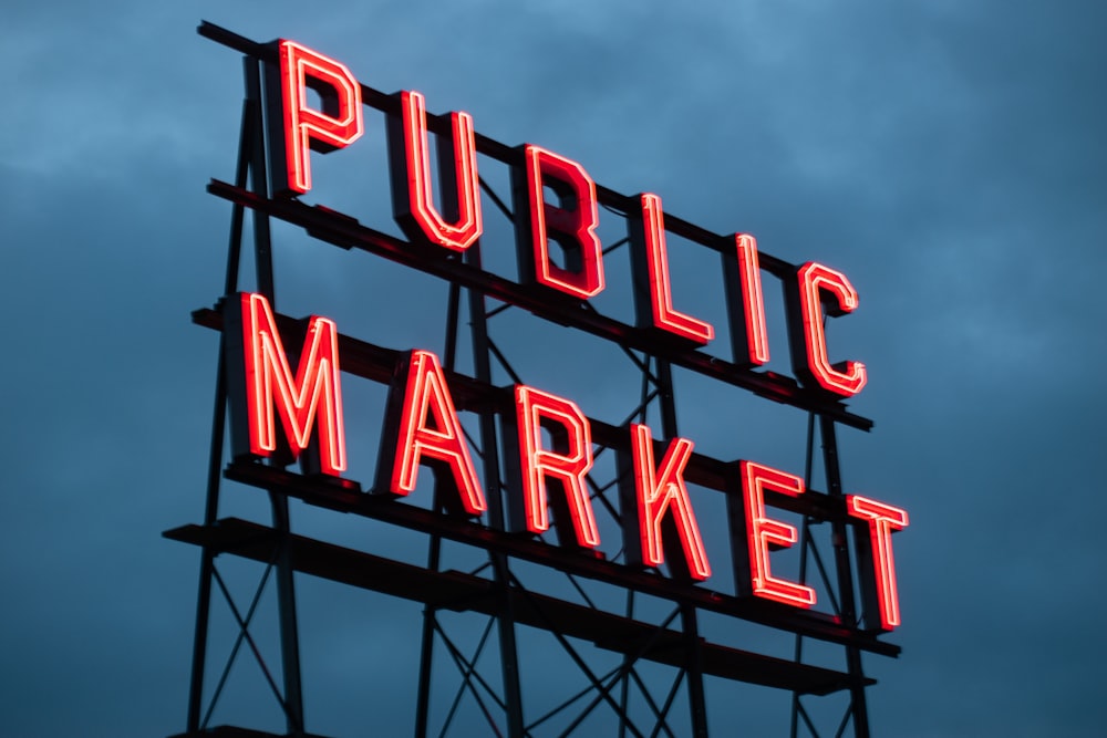 a public market sign lit up at night