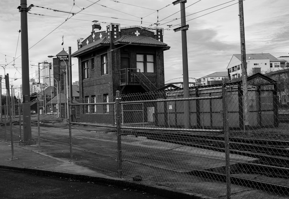 a black and white photo of a building behind a fence