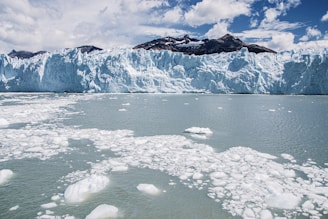 a large glacier with ice chunks floating in the water