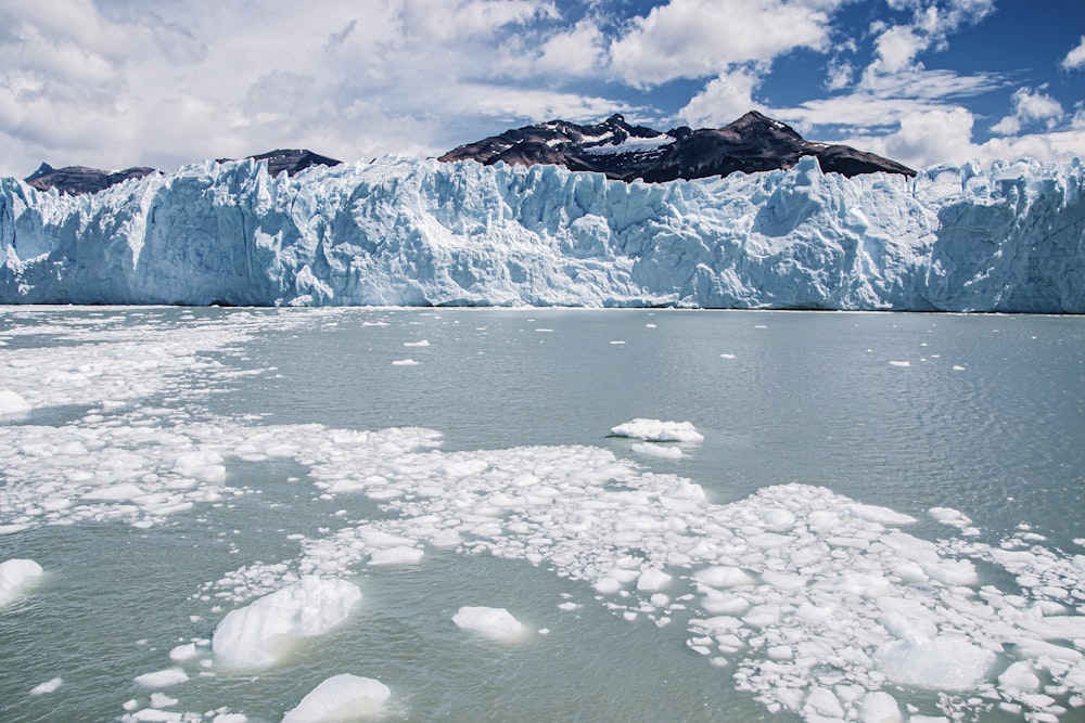 a large glacier with ice chunks floating in the water