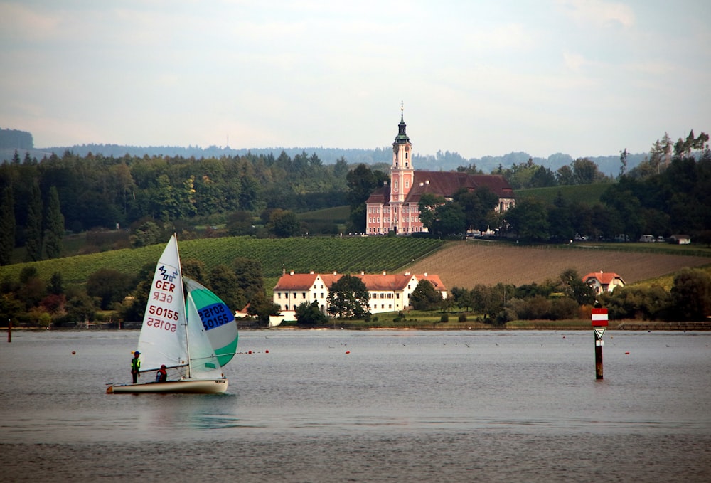 a sailboat on a lake with a church in the background