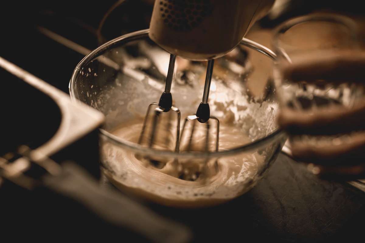 Stand mixer whipping baking batter in kitchen bowl