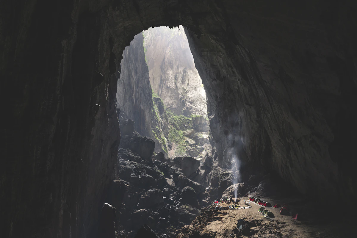 Tall opening in a cave roof letting daylight onto a boulder slope inside a giant limestone cave