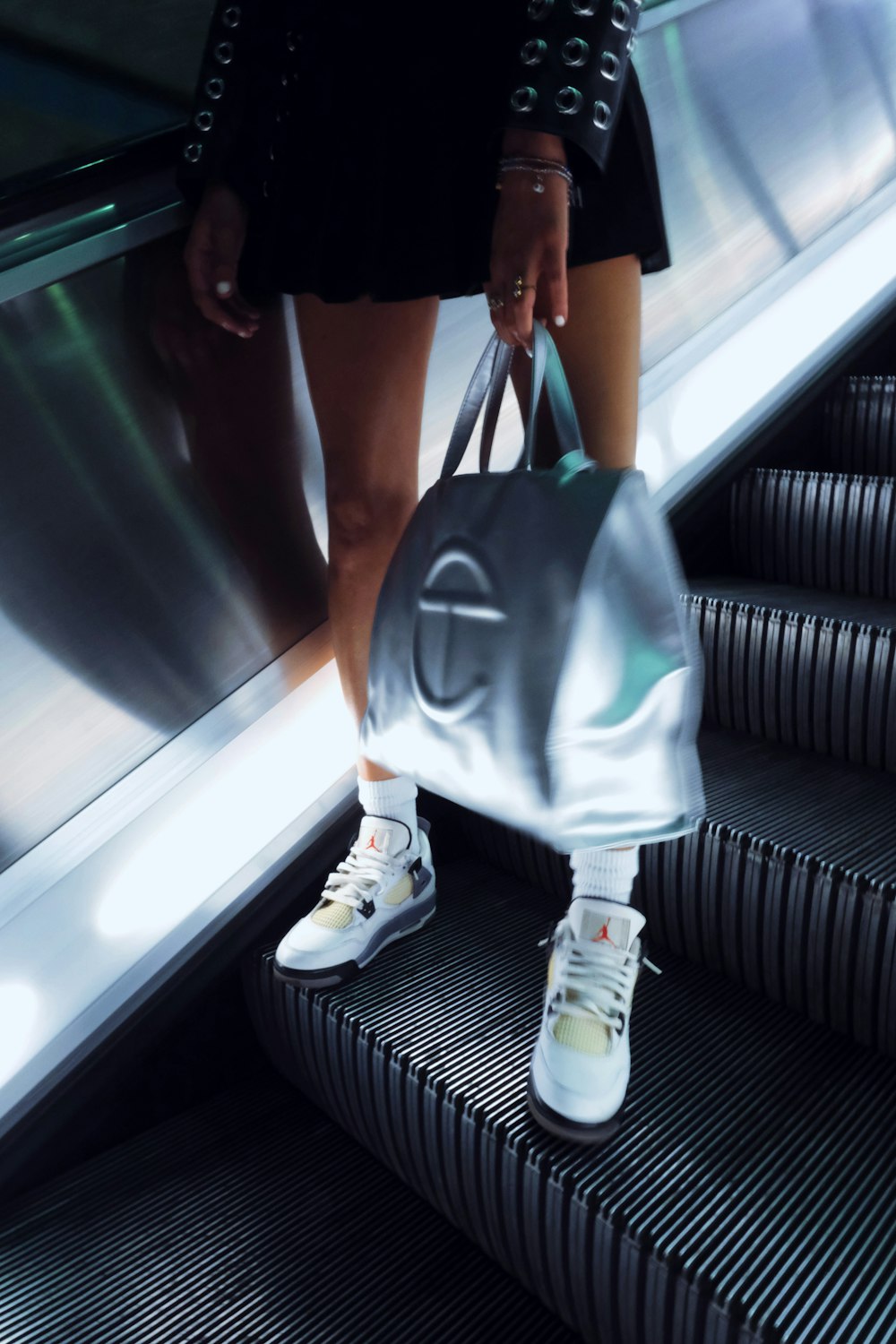 a woman is standing on an escalator with a bag