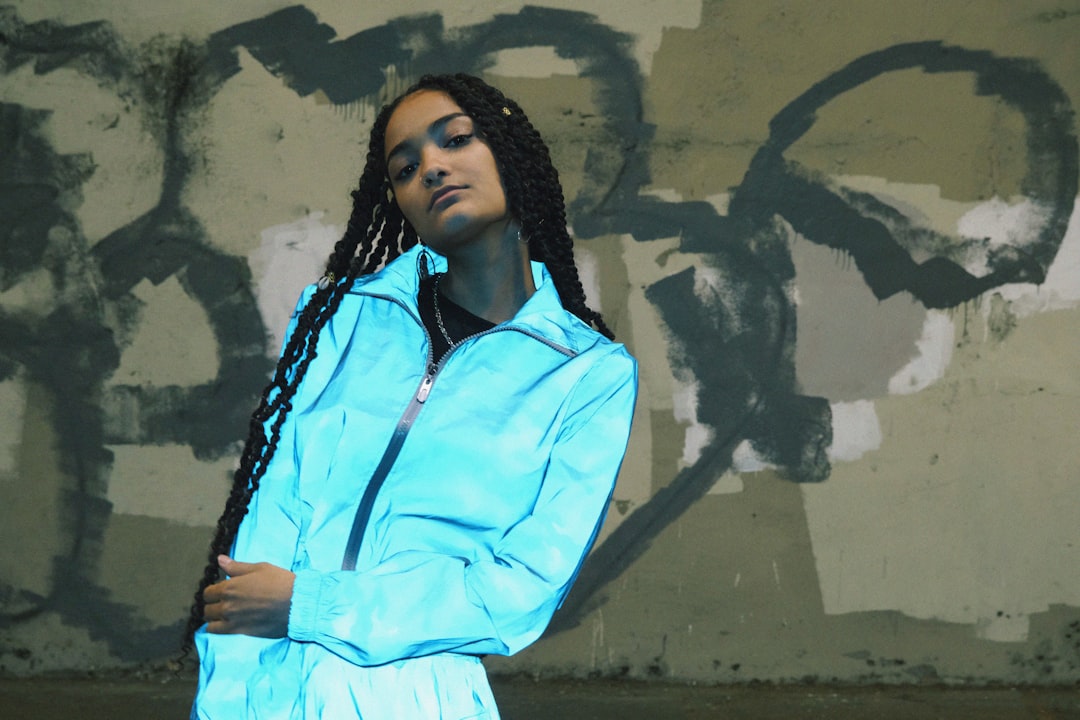 a woman with dreadlocks standing in front of a graffiti wall,